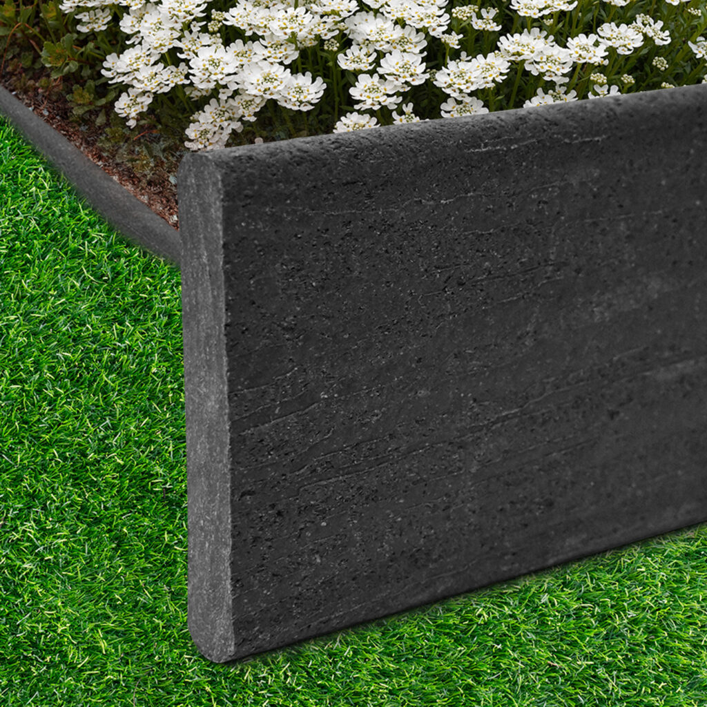 Black bender board edging beside artificial turf and white flowers