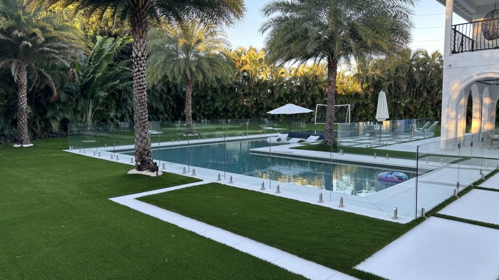 Artificial turf lawn beside a residential swimming pool, patio and palm trees